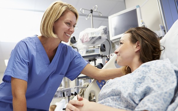 Laid Down Smiling Young Female Patient Talking To Nurse In Emergency Room